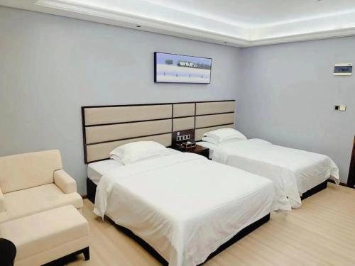 a hotel room with two beds and a chair at Li An Hotel Shantou Xiashan Central Bus Station Branch in Shantou