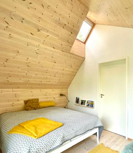 a bed in a room with a wooden ceiling at Architect-Designed House Close To Hornbæk in Tikøb