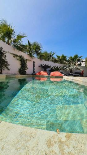 une grande piscine avec des parasols rouges devant un immeuble dans l'établissement Stunning Family Villa With Pool In Cap Dagde, au Cap d'Agde