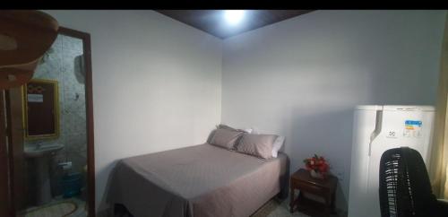 a small bedroom with a bed and a refrigerator at Suites Praia Forte Dunas in Cabo Frio