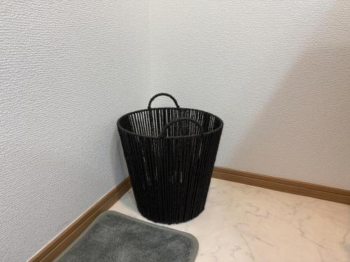 a black basket sitting in the corner of a room at ZenAbode茨城 in Ryūgasaki
