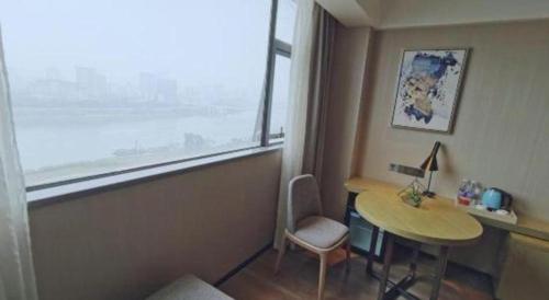 a room with a desk and a table and a window at Echarm Hotel Nanning Chaoyang Square River View in Nanning