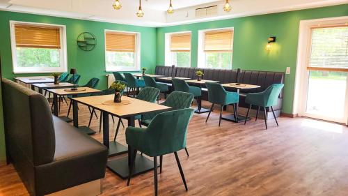 a restaurant with tables and chairs and green walls at Ferien Hotel Ostfriesland in Wiesmoor