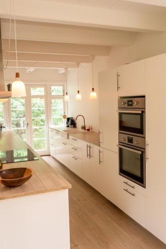 a kitchen with white cabinets and black appliances at Red Stone House By Dueodde Beach in Neksø
