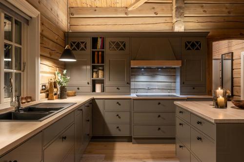 a kitchen with white cabinets and a wooden ceiling at Log Cabin Near Historic Senhovd in Veggli