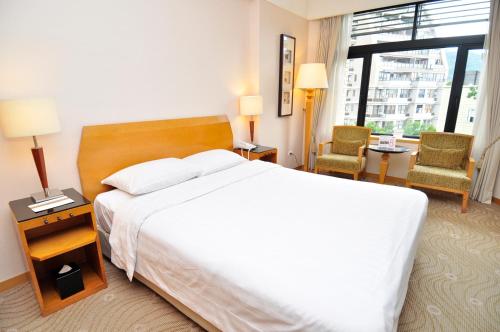 ein Hotelzimmer mit einem großen Bett und zwei Stühlen in der Unterkunft Spring City Resort in Taipeh