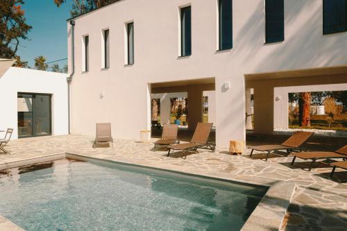 une piscine avec des chaises et une maison dans l'établissement Elegance And Nature Design House In Corsica, à Taglio-Isolaccio