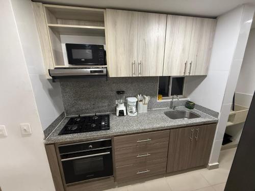 a small kitchen with a stove and a sink at Exclusivo apto / norte de valledupar hasta para 12 in Valledupar