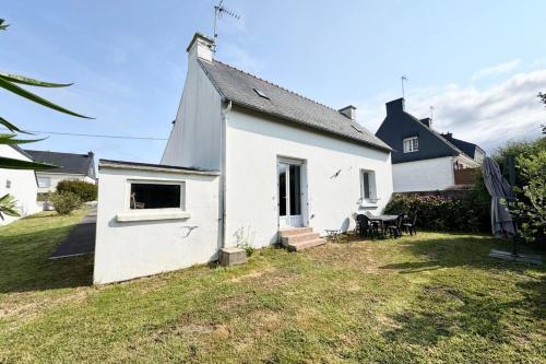 une maison blanche avec une table et des chaises dans une cour dans l'établissement Escapade à Ploemeur Maison avec jardin et parking, à Ploemeur