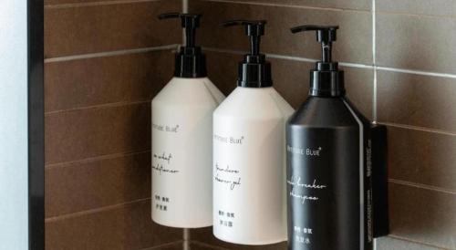 three bottles sitting on a shelf in a bathroom at Xana Hotelle Shenzheng South Station Foxconn in Shenzhen