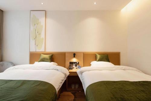 a room with two beds and a desk in it at Green Tree Inn Nanchang Zhongshan Road Bayiguan in Nanchang
