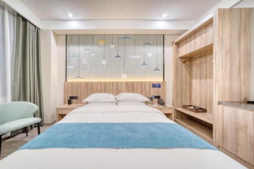 a bedroom with a large bed with a blue blanket at Gya Hotel Hangzhou Yuhang District Smart Town Wanda Plaza in Cangqian
