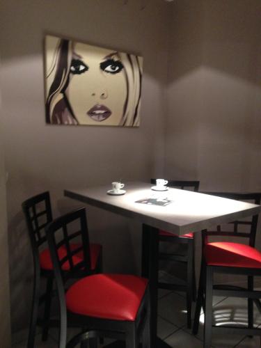a table with chairs and a painting on the wall at The Originals City, Hôtel Hélios, Roanne Nord in Mably