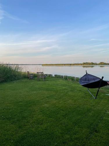 a lawn with a table and a bench next to the water at Protected Fjord Cabin With Fjord Views in Randers