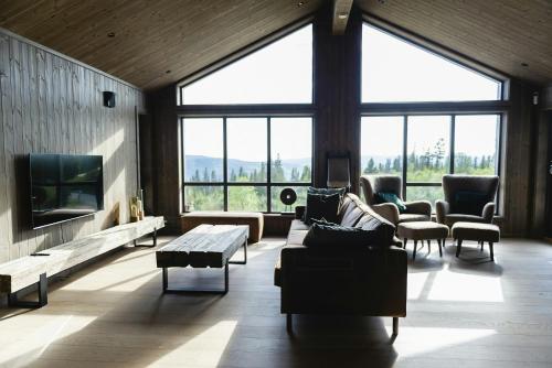 a living room with couches and a tv and large windows at Modern And Inviting Cabin In Valdres in Aurdal