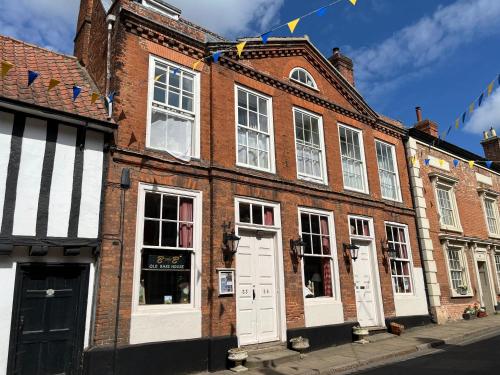 a brick building with white doors on a street at Walsingham Bakehouse in Little Walsingham