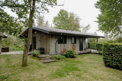 a small house in a yard with a tree at Warm 70S Vibe Near Limfjord in Løgstør