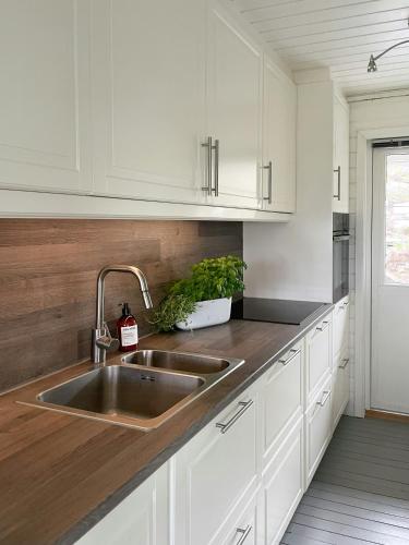 a kitchen with white cabinets and a stainless steel sink at Cozy Cabin With Sea View And Two Terraces in Tjøme