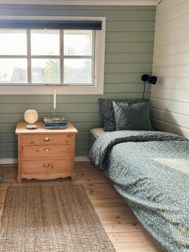 a bedroom with a bed and a dresser and a window at Charming Log Cabin Close To The Water And Hou in Hou