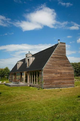 a large wooden barn with a black roof on a field at Architect-Designed House With Views In Uckermark in Gerswalde