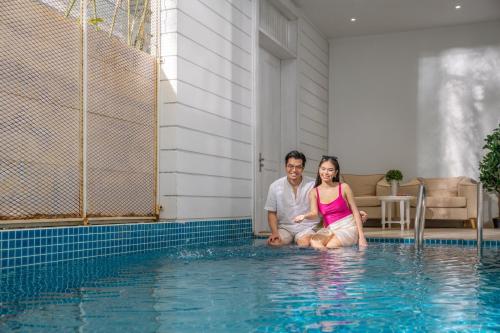 a man and woman sitting next to a swimming pool at The Salt Villas Da Nang - 250sm 3BR, 4BA & Kitchen in Danang