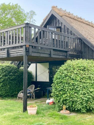 a wooden house with a deck and a bush at Hyggeligt Skovhus Med Fjordudsigt Nær Jægerspris in Kulhuse