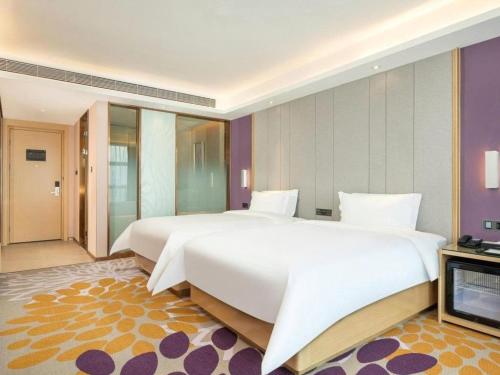 a large bedroom with two beds and a television at Lavande Hotel Zhongshan Xiaolan Taifeng in Jilong