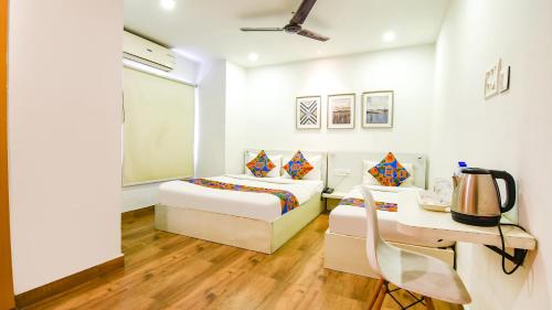 a bedroom with two beds and a table and a desk at Hotel Globe Express in Kolkata