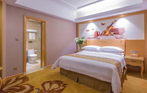 a hotel room with a large bed and a bathroom at Vienna Hotel Guangxi Fangcheng in Fangcheng