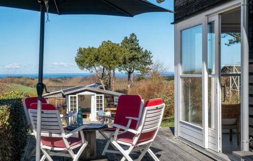 a table and chairs on a deck with an umbrella at Modern House With Sea View In Kårup in Fårevejle