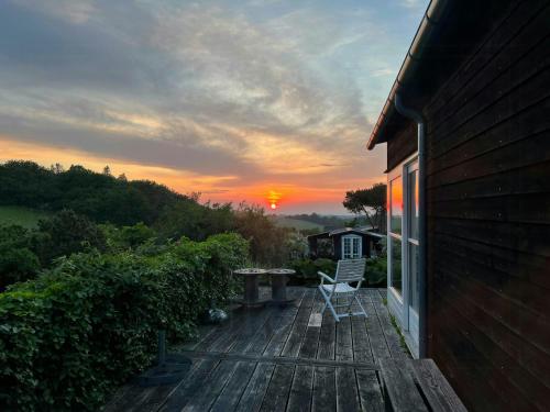 a deck with a table and a chair and a sunset at Modern House With Sea View In Kårup in Fårevejle
