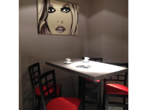 a table with chairs and a painting of a woman at The Originals City, Hôtel Hélios, Roanne Nord in Mably