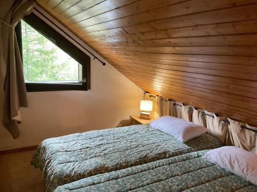 une chambre avec un lit avec un plafond en bois et une fenêtre dans l'établissement Bel appartement entier en style Chalet à Chamonix, à Chamonix-Mont-Blanc