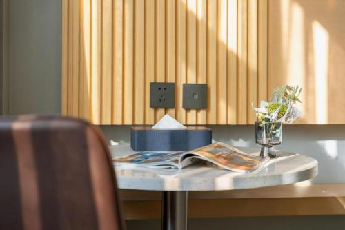 a table with a book and a vase of flowers on it at Borrman Hotel Jining High-tech Huangtun in Jining