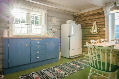 eine Küche mit einem Kühlschrank und einem Tisch in der Unterkunft Family-Friendly Cabin With Agricultural Idyll in Vestre Gausdal