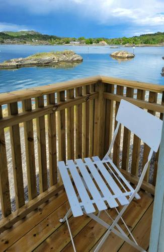 a white rocking chair sitting on a deck overlooking the water at Modern Captains House On Beautiful Skåtøy in Kragerø