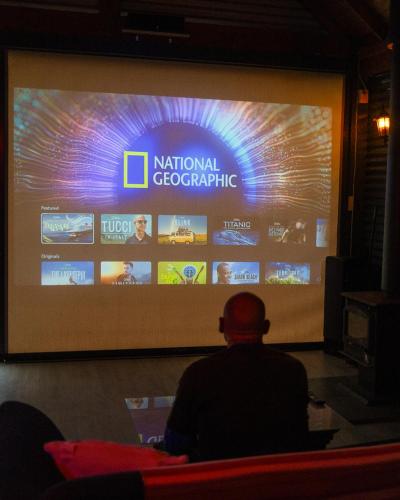 a man sitting in front of a large screen at Brett's Rest Nel in Kingscote