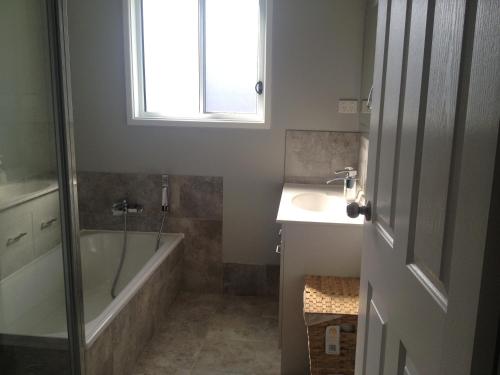 a bathroom with a tub and a sink and a window at Mystic Blue in Nowra