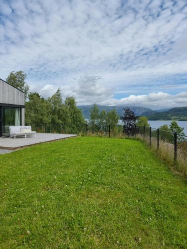 a grassy field with a bench in front of a building at Cabin By The Fjord With Rooftop Terrace On Randøy in Hjelmeland