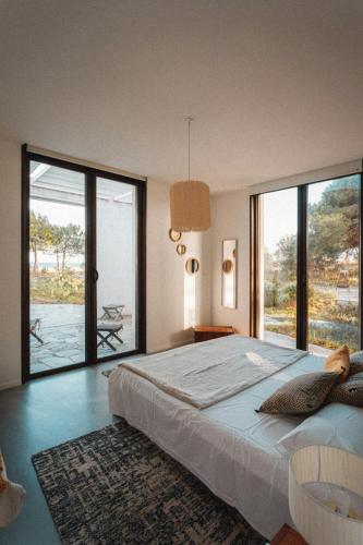 une chambre avec un grand lit et de grandes fenêtres dans l'établissement Elegant Architect-Designed Home In Upper Corsica, à Taglio-Isolaccio
