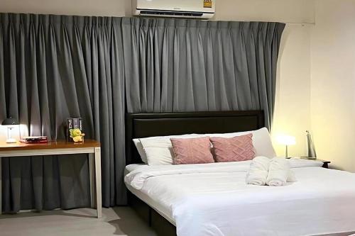 a bedroom with a bed with white sheets and pink pillows at BM Pool Villa Pattaya in Na Jomtien