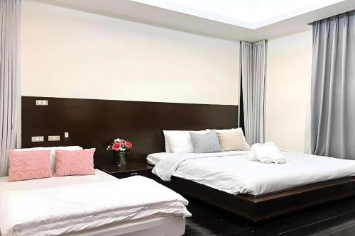 a bedroom with two beds with white sheets and pink pillows at BM Pool Villa Pattaya in Na Jomtien
