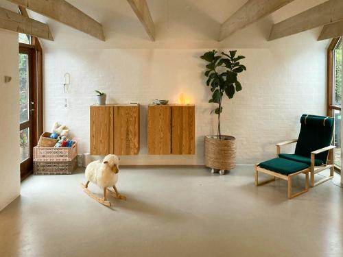 a dog standing in a living room with a chair at Beach House With Sauna By Norsminde Harbour in Malling