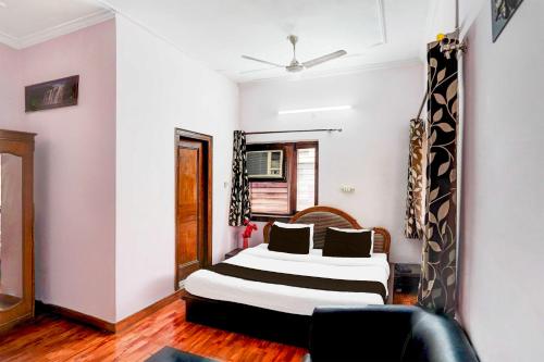 a bedroom with a bed and a chair in it at Collection O Krishna Nagar Chowk Near ONGC in Dehradun