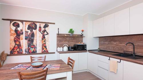 a kitchen with a wooden table and a kitchen with white cabinets at Flat Lora Pomorie in Pomorie