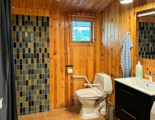 a wooden bathroom with a toilet and a sink at Idyllic Holiday Home Charm In Nr, Lyngby in Løkken