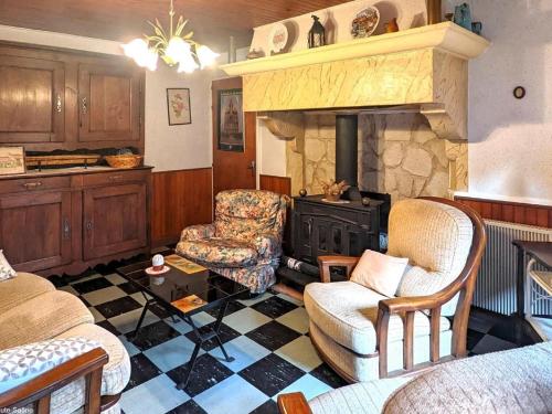 - un salon avec une cheminée en pierre et 2 chaises dans l'établissement Charmante maison de village en Haute-Saône avec cheminée - FR-1-583-479, à Morey