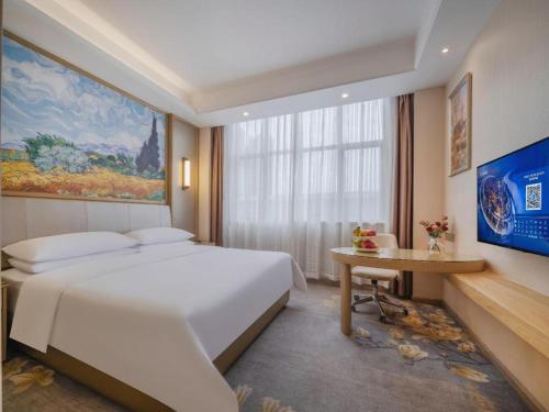 une chambre avec un grand lit blanc et une table dans l'établissement Vienna Hotel Shenzhen Pingshan Longtian Town, à Shenzhen