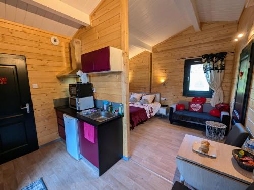 a room with a kitchen and a room with a bed at Chalet détente avec spa et sauna près des 1000 Étangs - FR-1-583-468 in La Vaivre