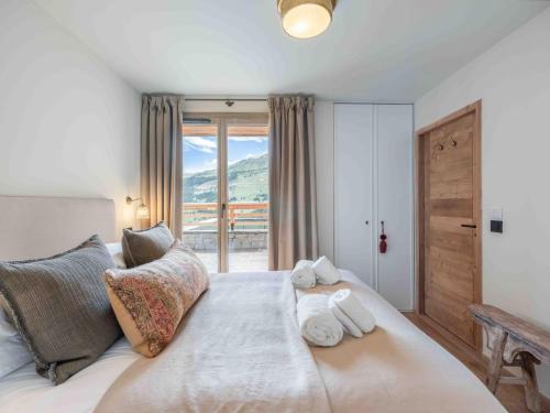 une chambre avec un grand lit avec une grande fenêtre dans l'établissement Appartement spacieux, ski au pied, parking inclus - FR-1-565-129, à Les Allues